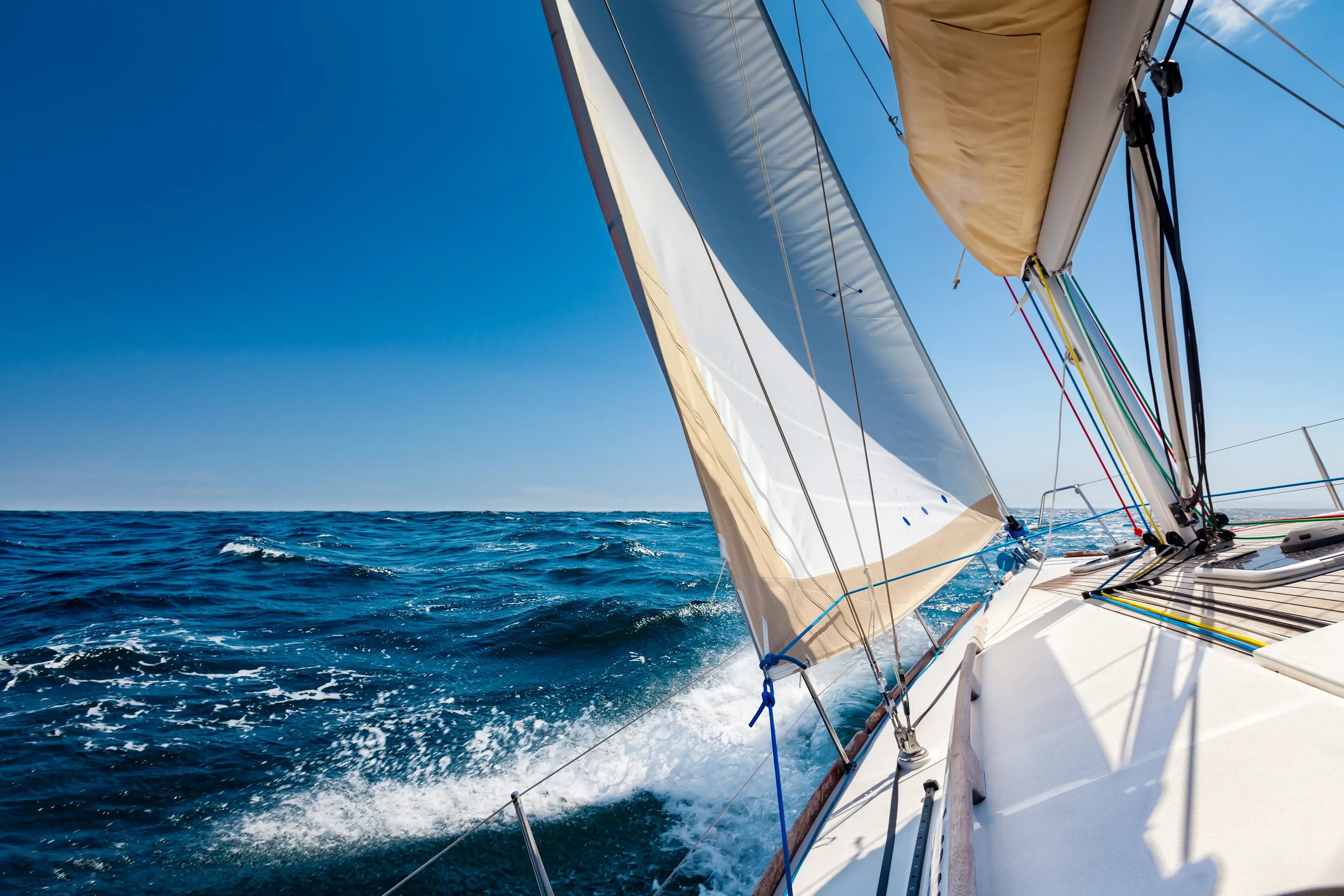 sail boat under sail on open water with clear horizon